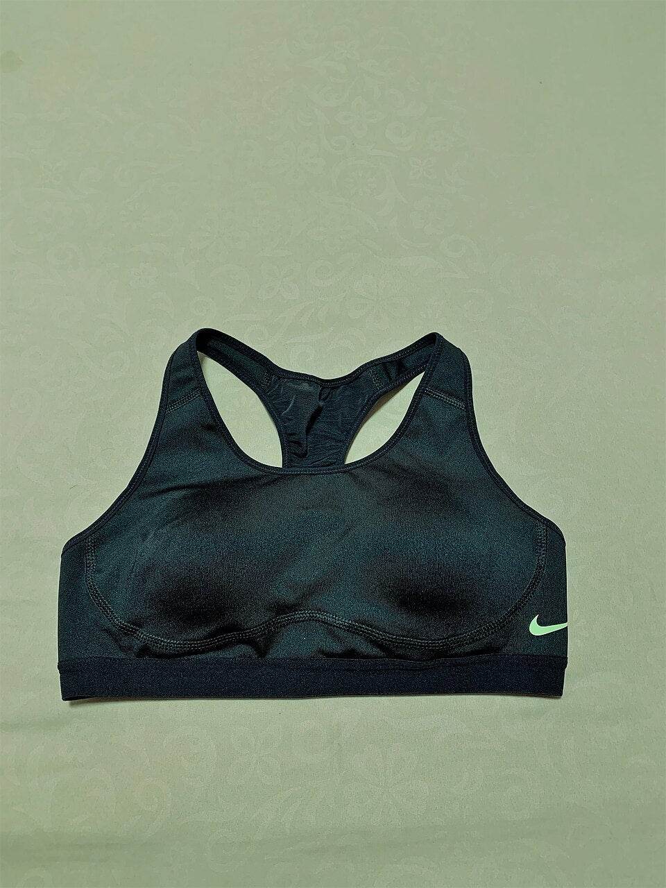 Front view of a black sports bra laid flat, showing the underband, neckline and straps.