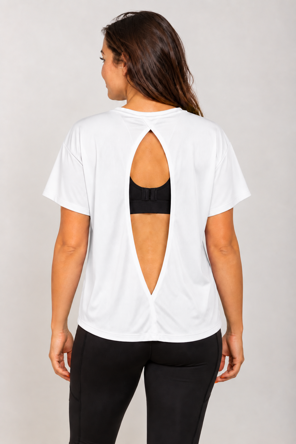 White open-back Running Woman T-shirt on a brunette model viewed from behind with a black running bra visible through the open back