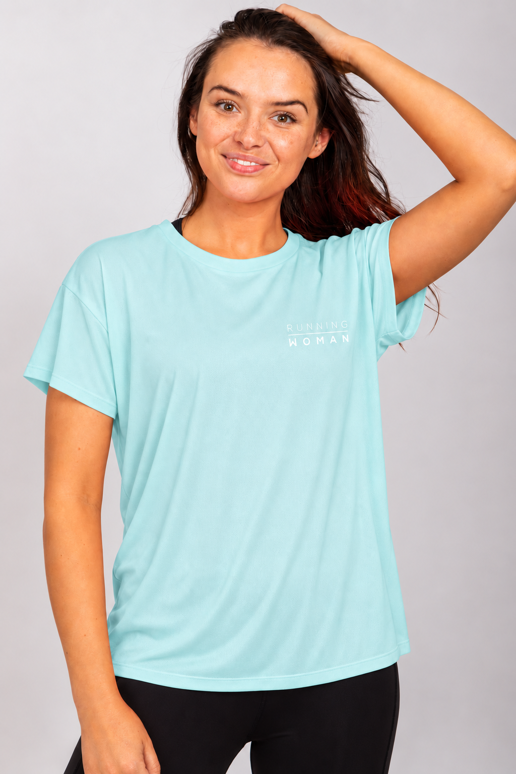 Mint open-back Running Woman T-shirt on a brunette model with one arm raised and her hand on her head