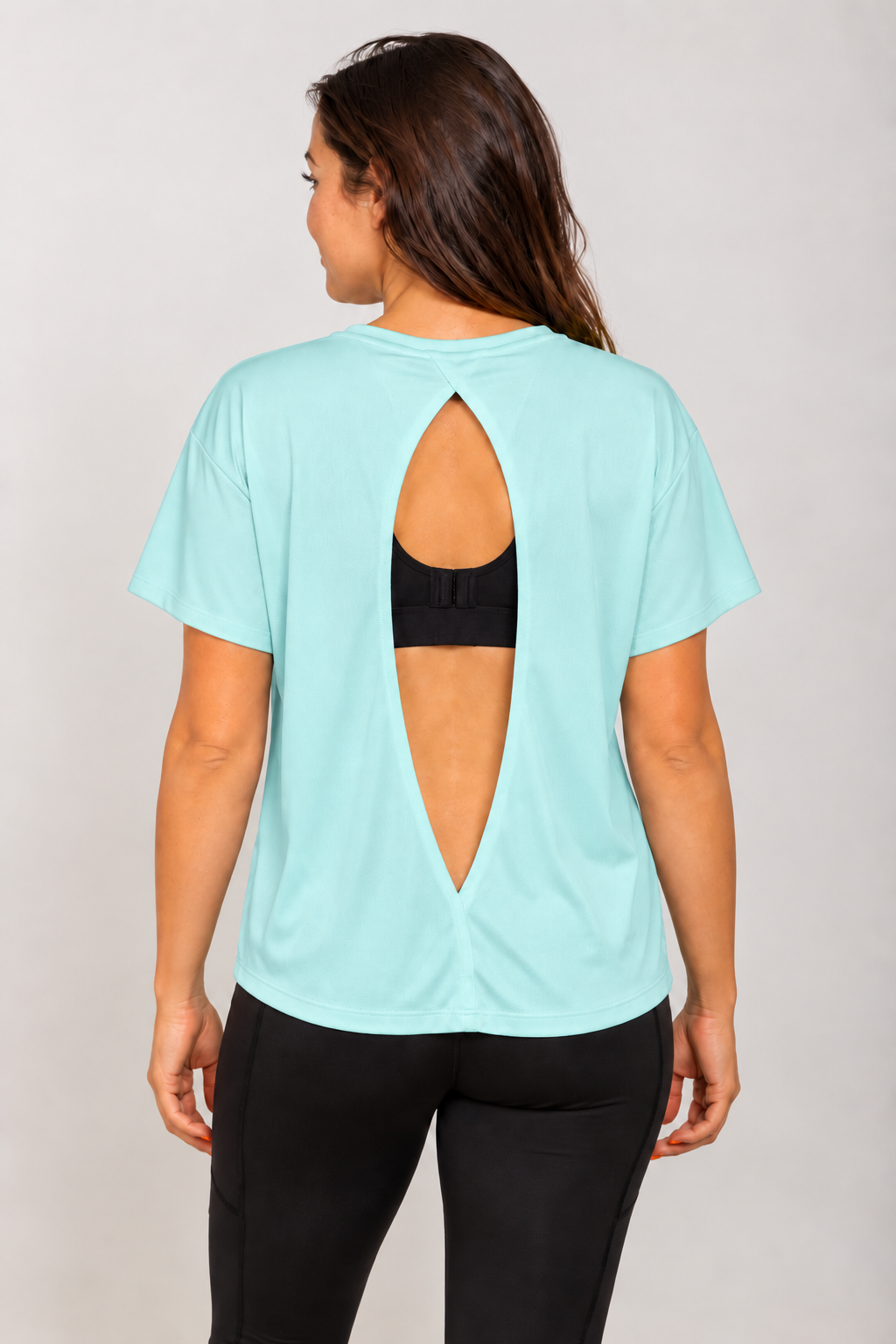 Mint open-back Running Woman T-shirt on a brunette model viewed from behind with a black running bra visible through the open back